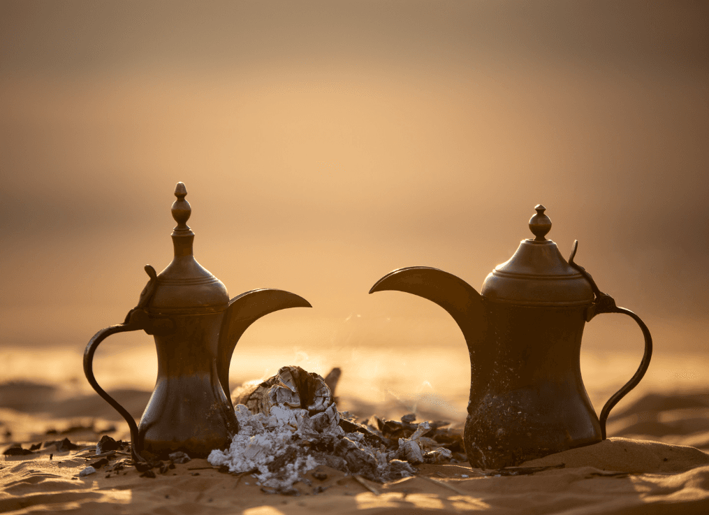 Traditional dallah coffee pots in the desert at sunrise